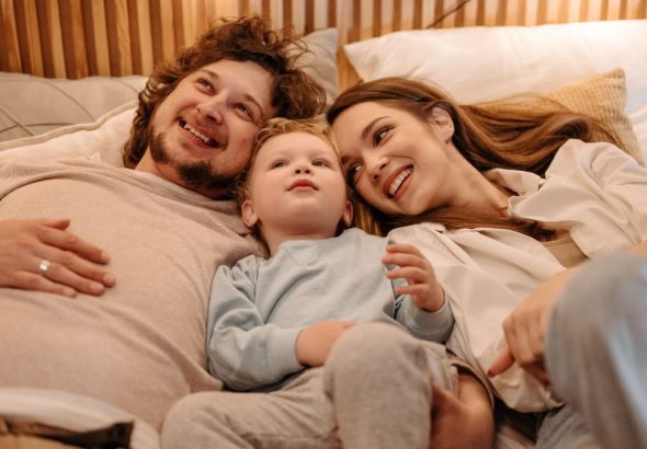 A joyful family bonding together while lying in bed, creating precious moments.