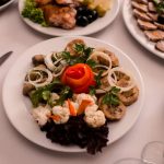 Beautifully arranged gourmet plates with meats, cheeses, and garnishes on a white table setting.